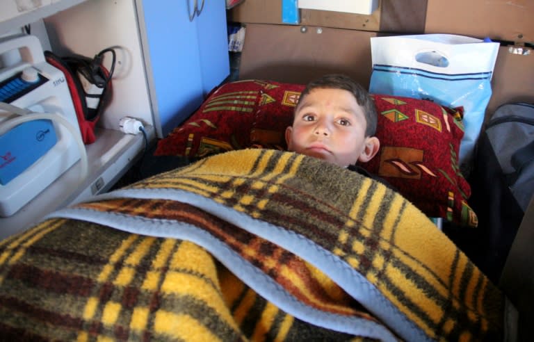 Nine-year-old Syrian Abdel Basset Al-Satuf (C) is seen inside an ambulance in the town of Al-Hbeit on February 17, 2017, ahead of being transferred to Turkey for medical treatment after being caught in a barrel bomb attack by regime forces