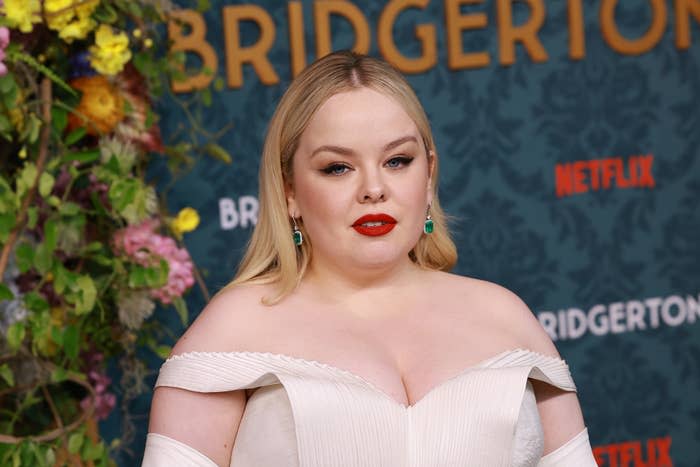 Nicola Coughlan in an off-the-shoulder gown poses at a Bridgerton Netflix event