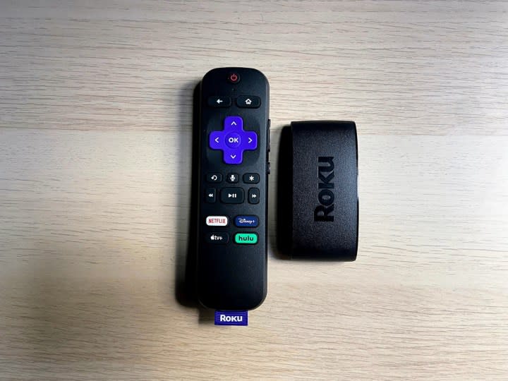 The Roku Express 4K Plus with remote on a wooden surface.