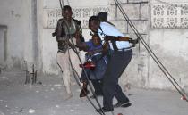 Police officers carry an injured man from the scene of a bomb attack outside the Jazira hotel in Mogadishu January 1, 2014. Three bombs exploded within an hour outside the hotel, frequented by government officials, in a heavily fortified district of the Somali capital on Wednesday, killing at least 11 people. (REUTERS/Feisal Omar)