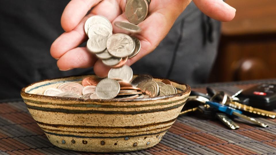 man placing pocket change in bowl.