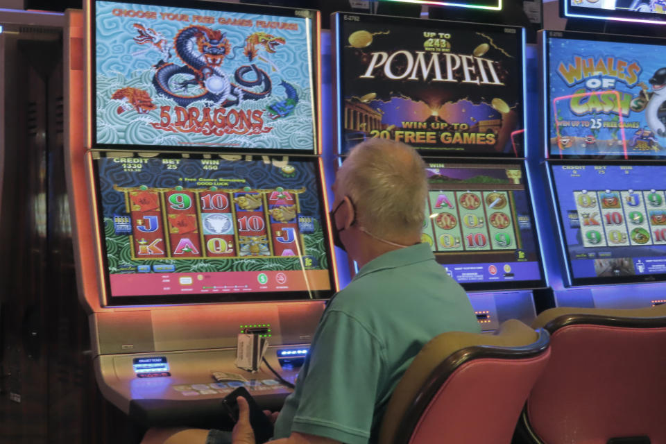 A man plays a slot machine at the Hard Rock Casino in Atlantic City N.J. on Aug. 8, 2022. On Sept. 16, 2022, New Jersey gambling regulators reported that the state's casinos, horse tracks that offer sports betting and the online partners of both types of gambling outlets won $470.6 million from gamblers in August, up nearly 10% from a year earlier. (AP Photo/Wayne Parry)