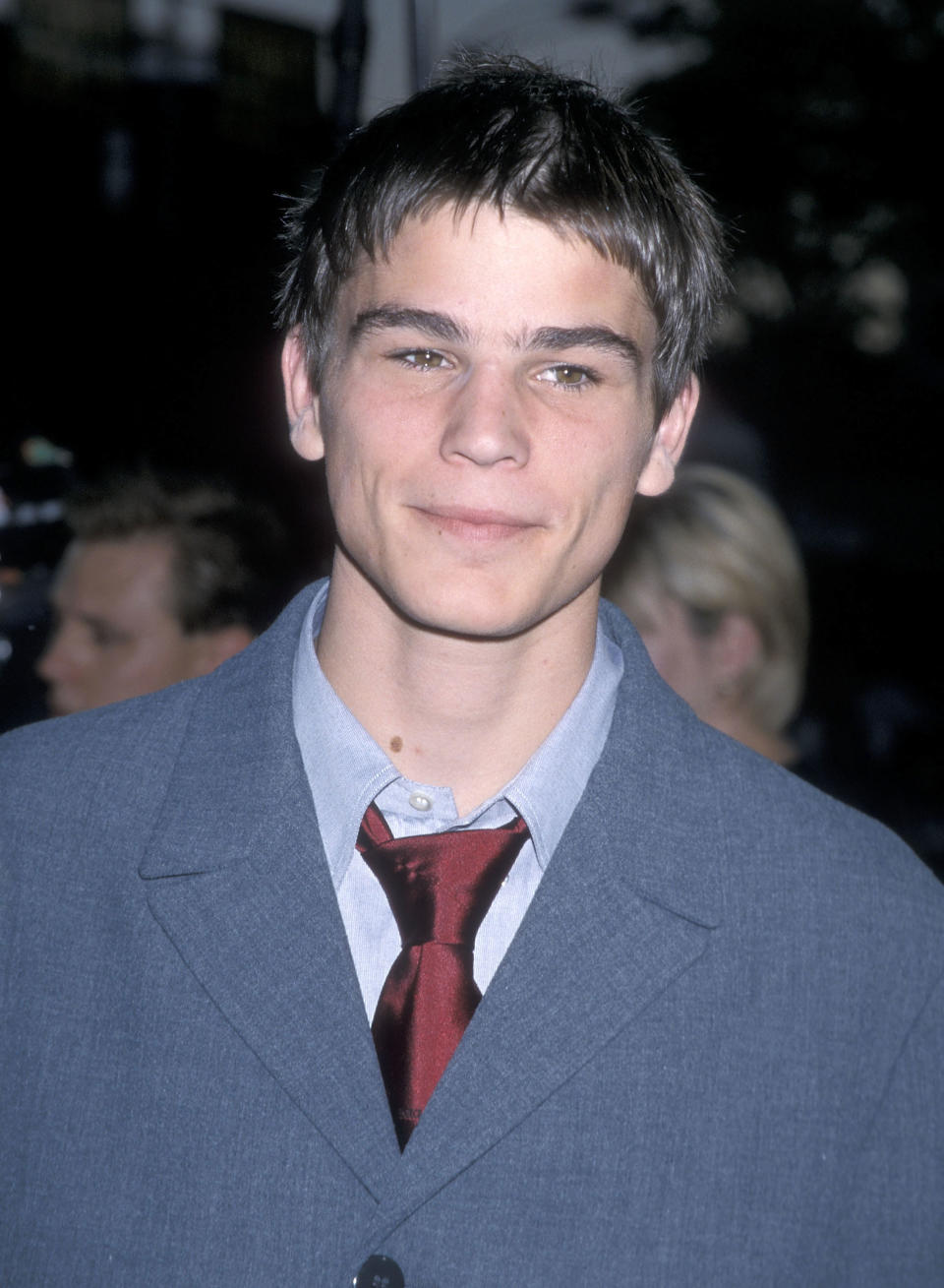 A person at an event wearing a suit with a tie, smiling at the camera