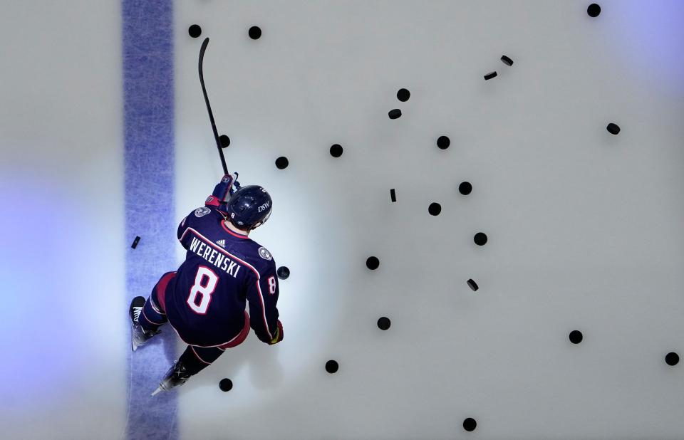 Columbus Blue Jackets defenseman Zach Werenski (8) scatters the pucks onto the ice for warm-ups prior to the NHL hockey game against the Chicago Blackhawks at Nationwide Arena in Columbus on Jan. 11, 2022. 