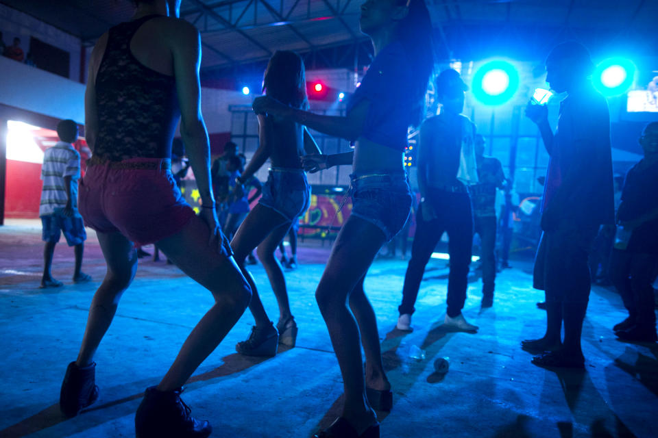 In this Dec. 8, 2012 photo, people dance during a funk "baile," or party, in a slum in western Rio de Janeiro, Brazil. A 2007 law that had made it virtually impossible to hold the traditional open-air funk parties in favelas was repealed in 2009, and the musical genre was recognized as a “cultural movement.” Dance face-offs between performers of “passinho,” a type of break dancing associated with Rio's funk scene, now come with corporate sponsorship. (AP Photo/Felipe Dana)