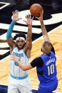 Orlando Magic guard Evan Fournier, right, takes a shot over Charlotte Hornets forward Miles Bridges, left, during the first half of an NBA basketball game, Sunday, Jan. 24, 2021, in Orlando, Fla. (AP Photo/John Raoux)