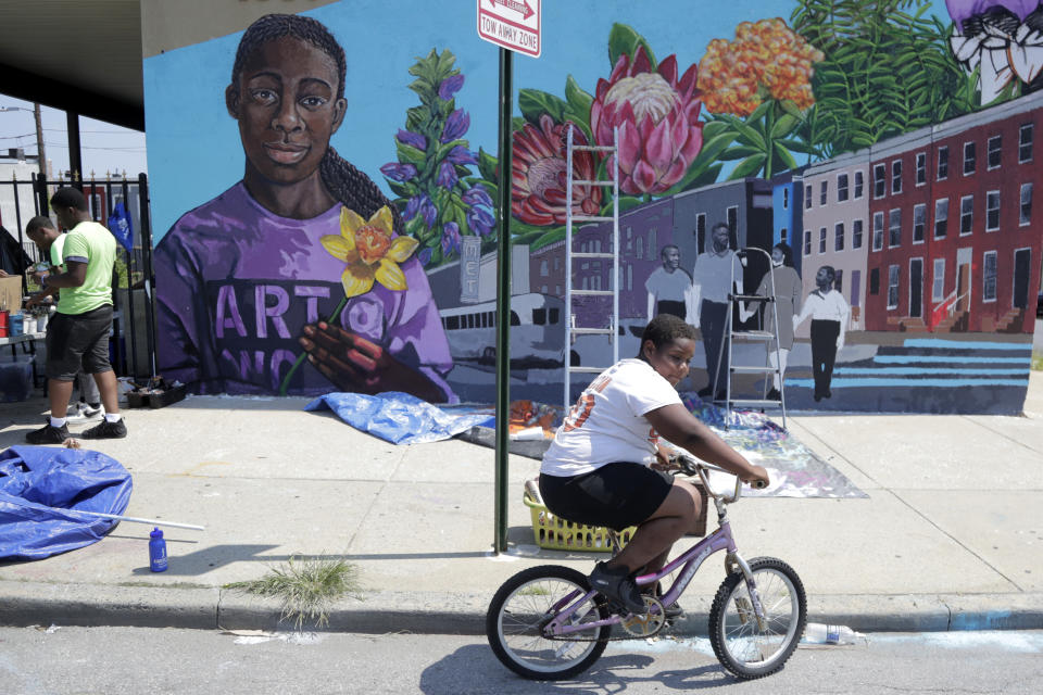 A boy rides his bicycle Monday, July 29. 2019 after volunteering to paint a mural outside the New Song Community Church in the Sandtown section of Baltimore. In the latest rhetorical shot at lawmakers of color, President Donald Trump over the weekend vilified Rep. Elijah Cummings majority-black Baltimore district as a "disgusting, rat and rodent infested mess" where "no human being would want to live." (AP Photo/Julio Cortez)