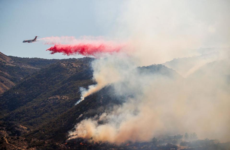 PHOTO: A plane drops fire retardant during the Highland Fire in Aguanga, Calif., on Oct. 31, 2023. (Ethan Swope/Bloomberg via Getty Images)