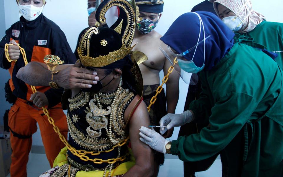 A healthcare worker injects a dose of Sinovac's vaccine to a man dressed in Indonesia's traditional human puppet costume known as 'Wayang', as Indonesia drives mass vaccination for the coronavirus at a hospital in Solo, Central Java province, - Reuters/Antara Foto/Maulana Surya