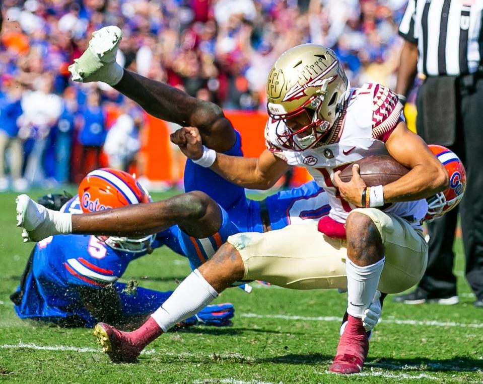 Florida Gators safety Trey Dean III (0) brings down Florida State Seminoles quarterback Jordan Travis (13) in the first half Saturday at Ben Hill Griffin Stadium in Gainesville. [Doug Engle/Ocala Star-Banner]