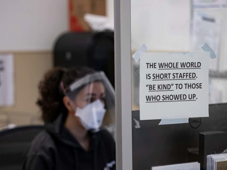 A nurse sits behind a sign that reads ‘the whole world is short staffed. Be kind to those who showed up,’ in the Humber River Hospital emergency department on Jan. 13, 2022. (Evan Mitsui/CBC - image credit)