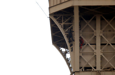 An unidentified man climbs the Eiffel Tower, which had to be evacuated, next to a Paris fire brigade specialist in Paris, France, May 20, 2019. REUTERS/Charles Platiau