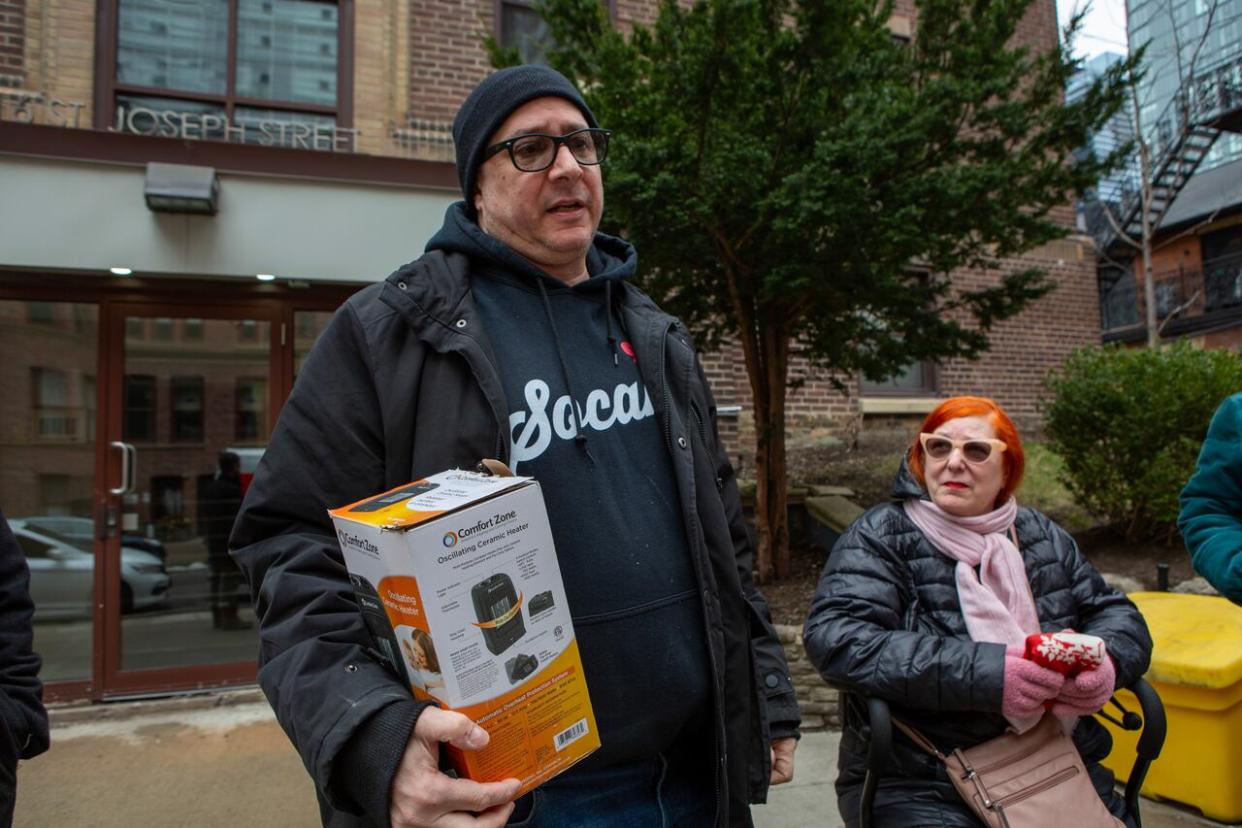 Howard Druckman, a long-time resident of 16 St. Joseph, holds one of the space heaters issued to residents after the building's boiler broke down.  (Richard Davis/CBC - image credit)