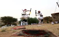 Los hombres que llevan a cabo esta curiosa tradición disparan hacia una alfombra colocada en el suelo, al tiempo que dan un brinco para no resultar heridos.<br><br>Crédito: REUTERS/Mohamed Al Hwaity