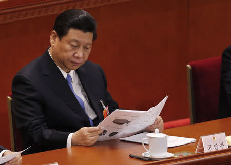 China's Communist Party Chief Xi Jinping reads at the Great Hall of the People during the third plenary session of the National People's Congress (NPC) in Beijing March 10, 2013. REUTERS/Kim Kyung-Hoon/Files