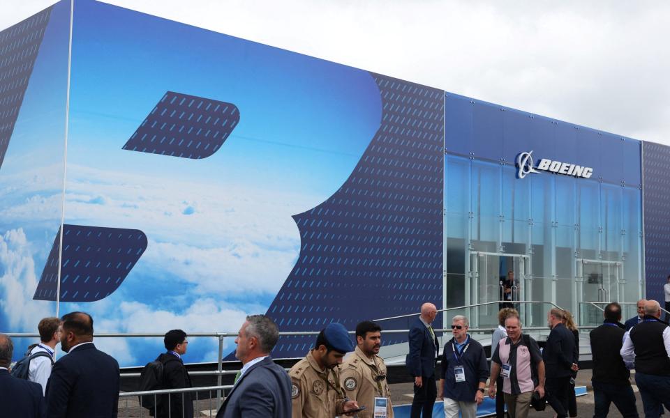 Attendees walk past Boeing branding at the Farnborough Airshow yesterday