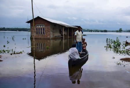 Villagers are transported on a boat towards a safer place at a flooded village in Nagaon district