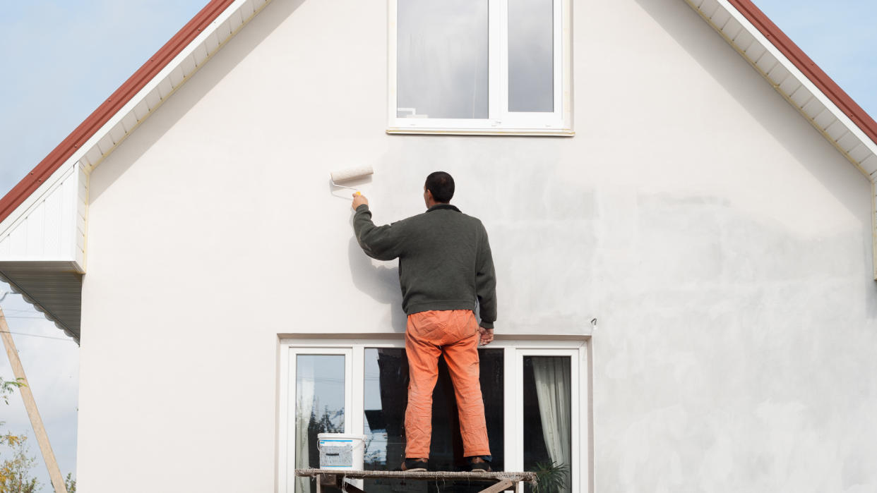 construction worker is painting a wall with a roller.