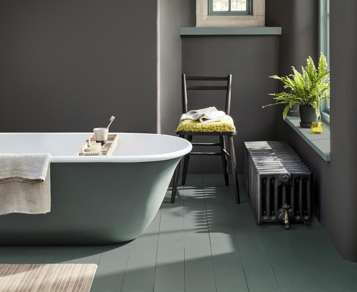  A bathroom with a free-standing bath painted in two shades of green. 
