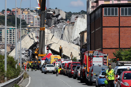 FILE PHOTO: Firefighters and rescue workers stand at the site of the collapsed Morandi Bridge in the port city of Genoa, Italy August 15, 2018. REUTERS/Stefano Rellandini/File Photo