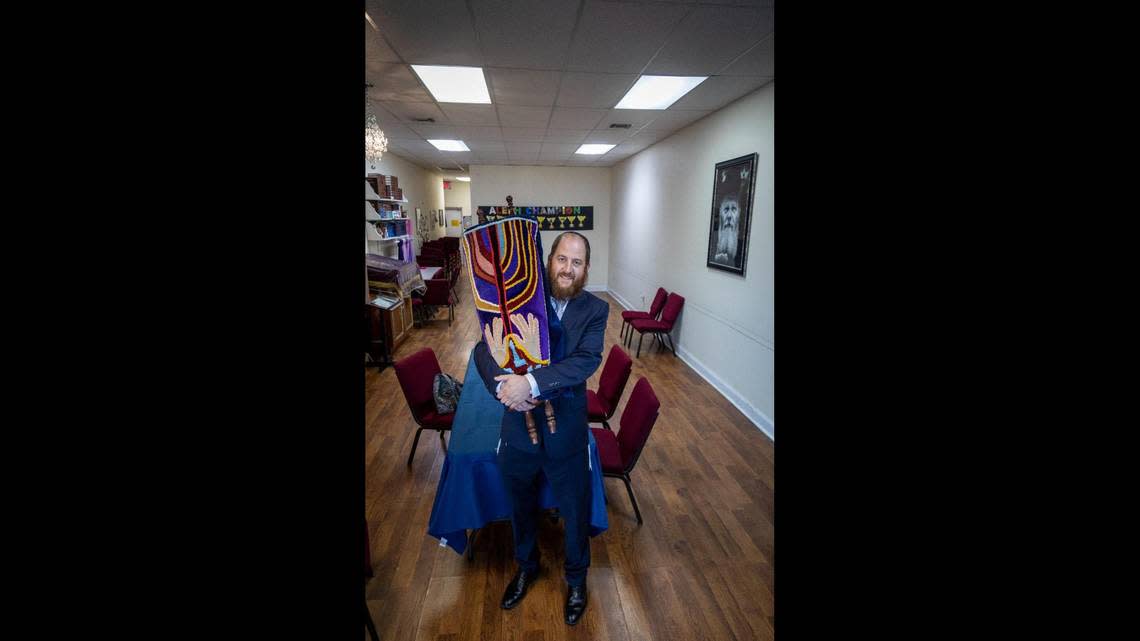 Rabbi Yossi Wolff holds a Torah inside the current location of the Chabad in a strip mall on Old Cutler Road on Nov. 23, 2022.