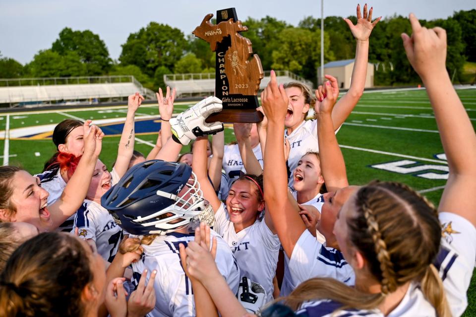 Haslett-Williamston's Ree Baetz, center, hoists the regional championship trophy in the air as the Vikings celebrate after defeating DeWitt on Friday, June 2, 2023, at DeWitt High School.