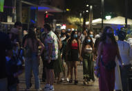 A group of people wearing face masks walk on the street In Fuengirola, near Malaga, Spain, Saturday, Aug. 8, 2020. The increase in Spain of coronavirus outbreaks associated with nightlife has set off alarms in recent days, mainly in tourist areas where pubs and discos are full before the summer tourist campaign. (AP Photo/Jesus Merida)