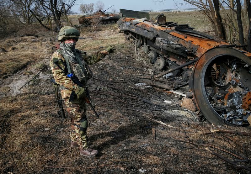 FILE PHOTO: A Ukrainian serviceman stands near the wreck of a Russian Armoured Personnel Carrier on the front line in the Kyiv region