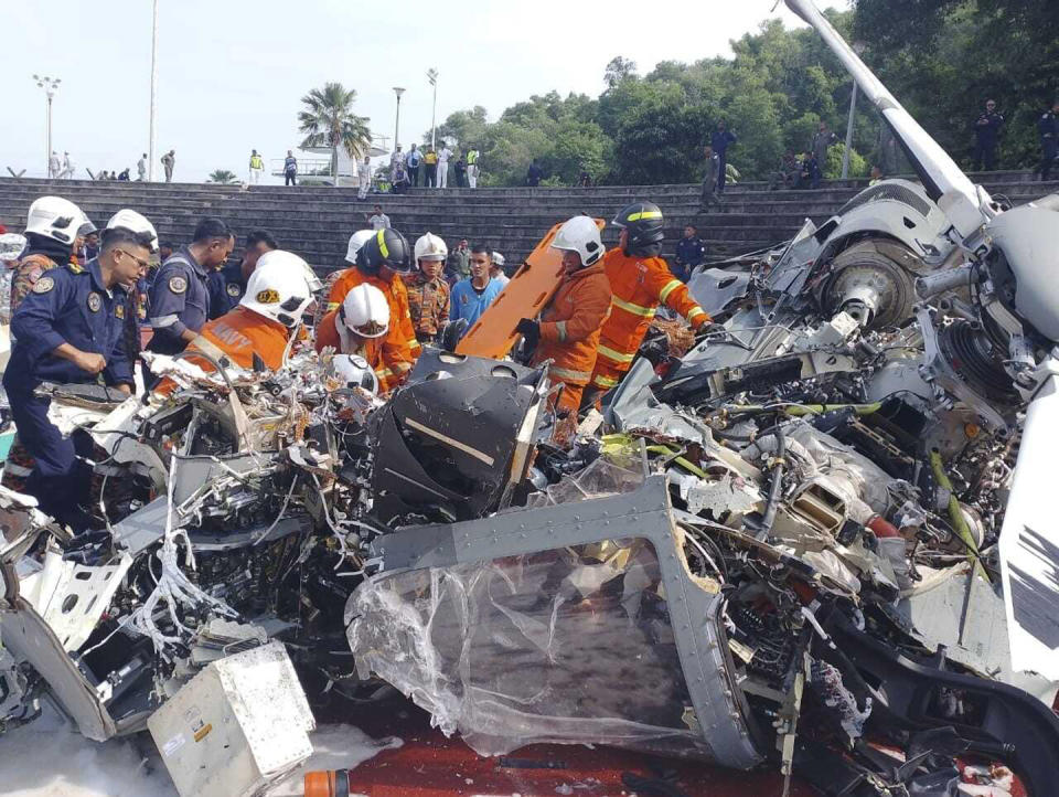 CORRECTS THE SOURCE - In this photo released by Fire & Rescue Department of Malaysia, fire and rescue department inspect the crash site of two helicopter in Lumur, Perak state, Monday, April 23, 2024. Malaysia's navy says two military helicopters collided and crashed during a training session, killing all 10 people on board. (Fire & Rescue Department of Malaysia via AP)