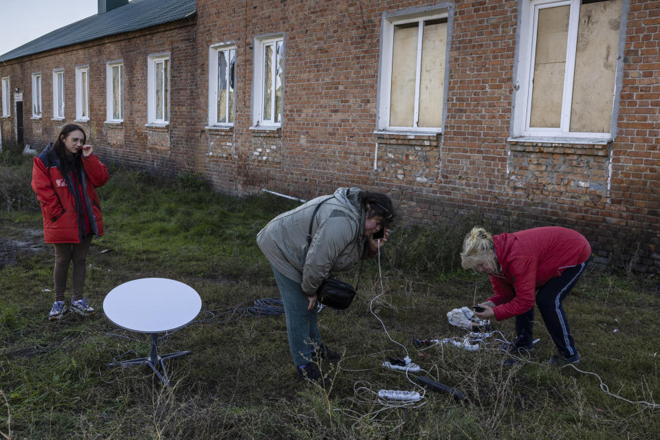 Residentes utilizan una antena parabólica Starlink y un generador para conectarse a internet y cargar sus teléfonos en Stari Saltiv, Ucrania, el 17 de octubre de 2022. (Ivor Prickett/The New York Times)