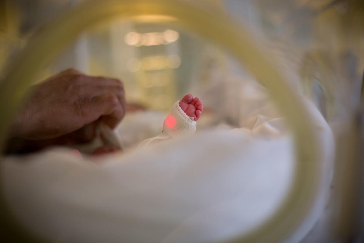 Newborn baby's feet and dad's hand