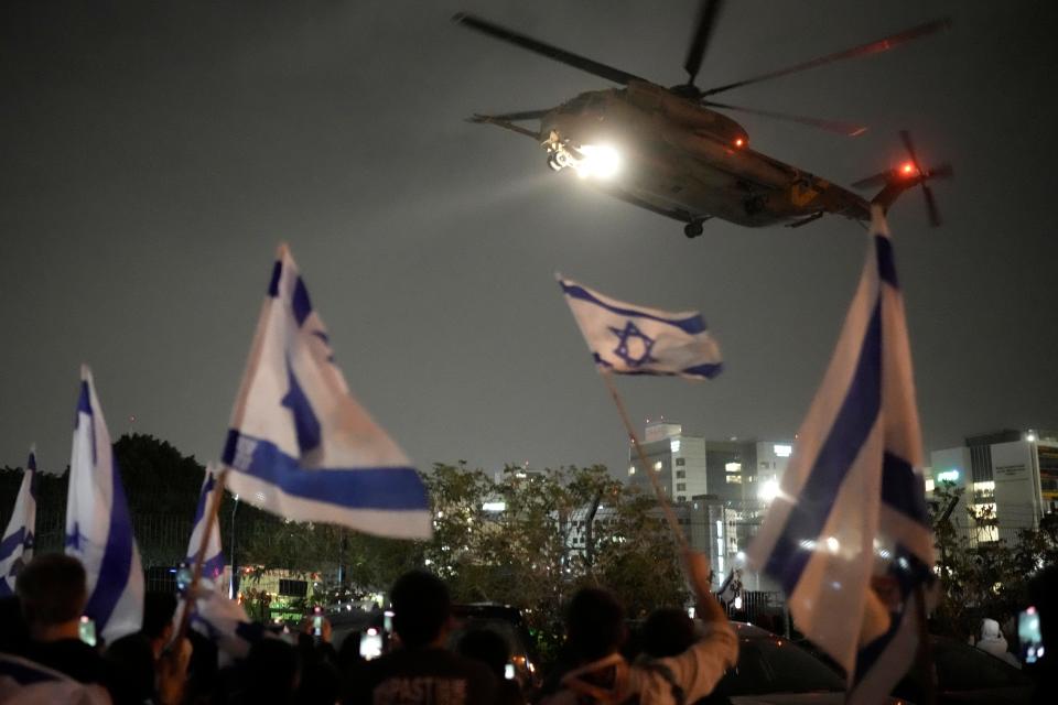 People wave Israeli flags as a helicopter carrying hostages released from Gaza by Hamas arrives at the helipad of the Schneider Children's Medical Center in Petah Tikva, Israel, Sunday, Nov. 26, 2023. (AP Photo/Leo Correa) ORG XMIT: DV533