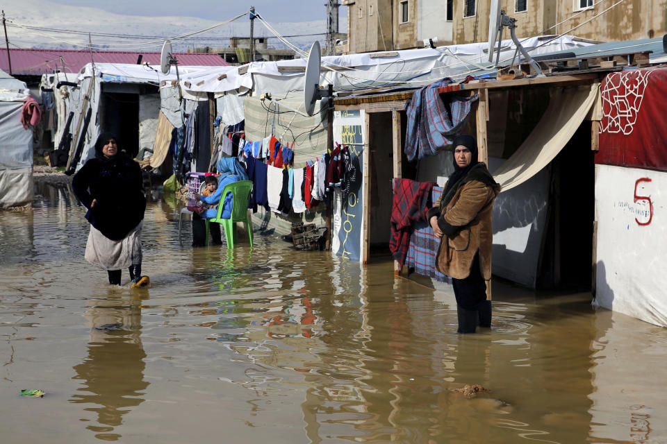 Syrian refugees stand in a pool of mud and rain water at a refugee camp, in the town of Bar Elias, in the Bekaa Valley, Lebanon, Thursday, Jan. 10, 2019. A storm that battered Lebanon for five days displaced many Syrian refugees after their tents got flooded with water or destroyed by snow. (AP Photo/Bilal Hussein)