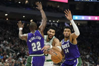 Boston Celtics' Jayson Tatum, center, loses control of the ball between Milwaukee Bucks' Khris Middleton, left, and Giannis Antetokounmpo, right, during the first half of an NBA basketball game Thursday, March 30, 2023, in Milwaukee. (AP Photo/Aaron Gash)