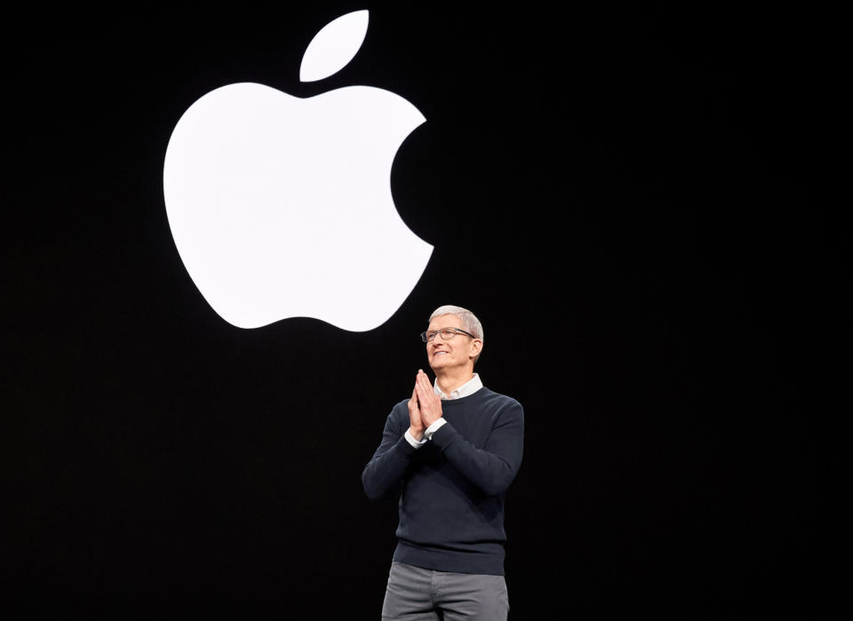 Apple CEO Tim Cook on stage with the Apple logo on the screen in the background.