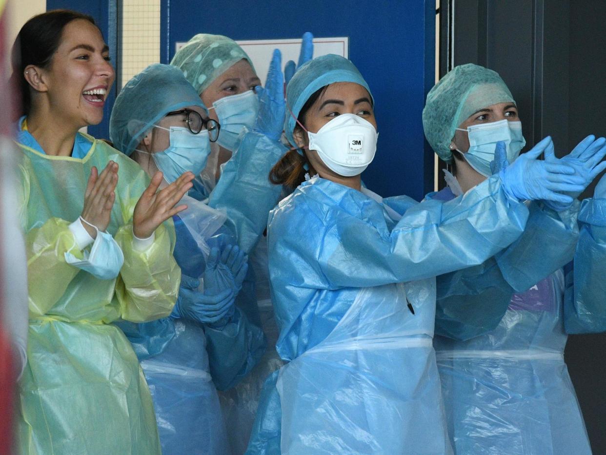 NHS workers wearing personal protective equipment including a face mask, gloves and aprons, as a precautionary measure against COVID-19 enjoy a national "clap for carers" to show thanks for the work of Britain's NHS (National Health Service) Aintree University Hospital in Liverpool, north-west England on 14 May, 2020: Oli Scarff/AFP via Getty Images