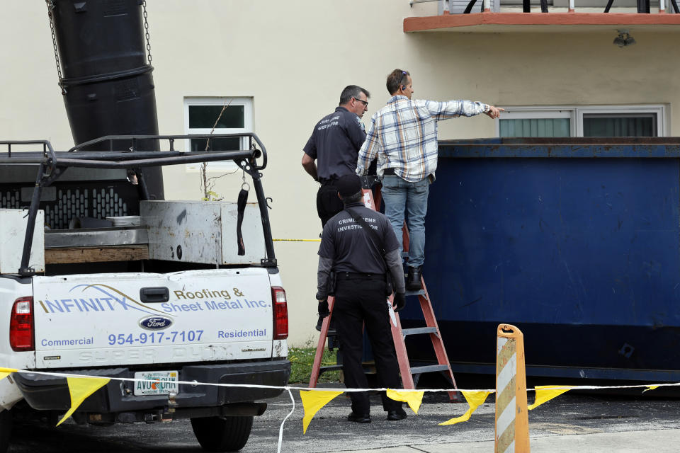 A man standing with a crime scene investigator points to the inside of a large trash bin outside of an apartment complex in Hollywood, Fla., where construction workers found a dead baby on Monday, Jan. 8, 2024. (Amy Beth Bennett/South Florida Sun-Sentinel via AP)