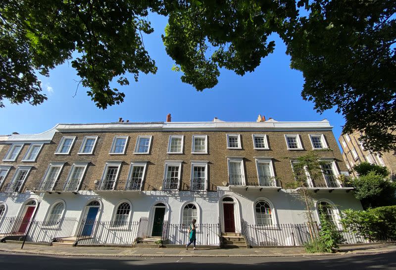 A woman walks past houses on a street in Islington, London