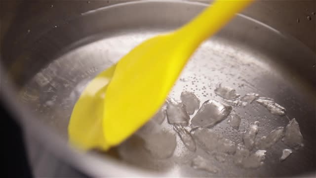 Melting rock sugar in boiling water with a spatula