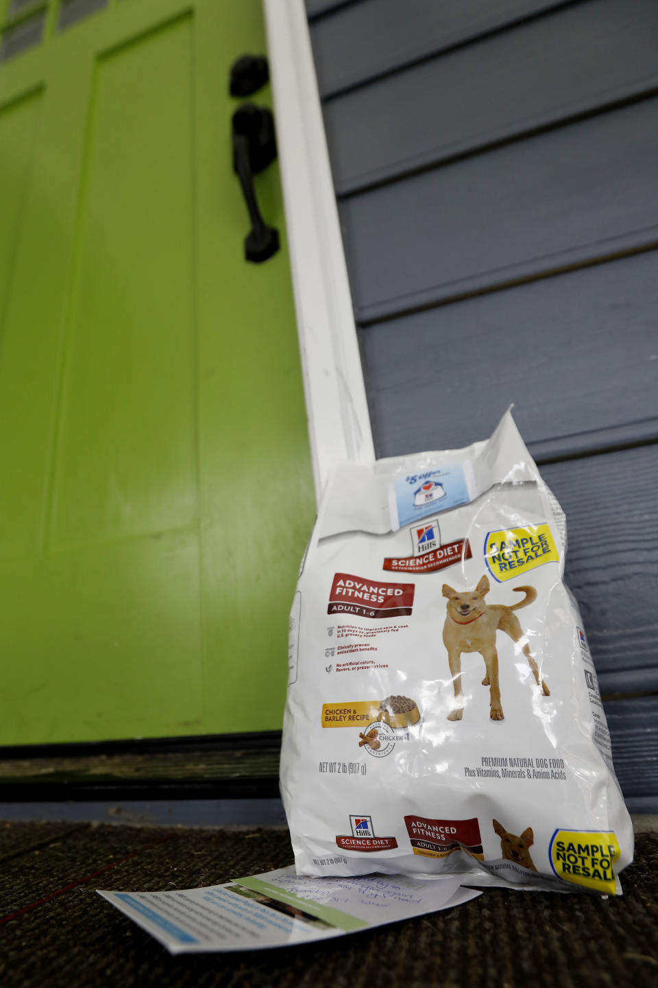 In this Tuesday, Aug. 27, 2019 photo, a bag of dog food and a resource card about LifeLine Animal Project's Pets for Life program is left on a dog owner's doorstep in Atlanta. Outreach coordinators go door-to-door in mostly low-income neighborhoods to explain the program's services, such as free spay and neuter surgeries. When coordinators knock and hear barking, but no one answers the door, they return with food and a handwritten note. (AP Photo/Andrea Smith)