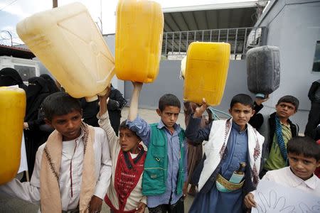 Boys hold up jerrycans to represent drinking water during a protest against a Saudi blockade of Yemen's ports, outside the United Nations' offices in Sanaa, Yemen October 19, 2015. REUTERS/Khaled Abdullah