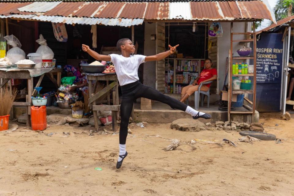 Anthony Madu performs a ballet dance routine in front of his mother's shop in Okelola street in Ajangbadi, Lagos (AFP via Getty Images)