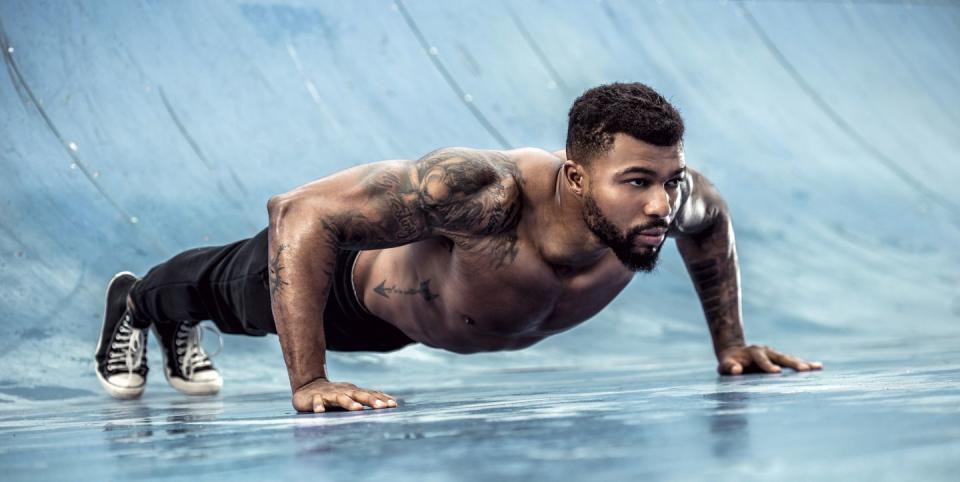 tattooed physical athlete doing pushups on sports field