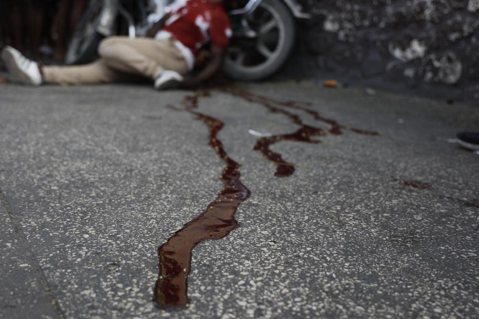 El cadáver de un hombre yace en medio de un charco de sangre junto a su moto, en el vecindario de Delmas, en Puerto Príncipe, Haití, el 8 de marzo de 2024. Según los testigos, fue baleado por dos hombres no identificados que iban en motocicleta. (AP Foto/Odelyn Joseph)