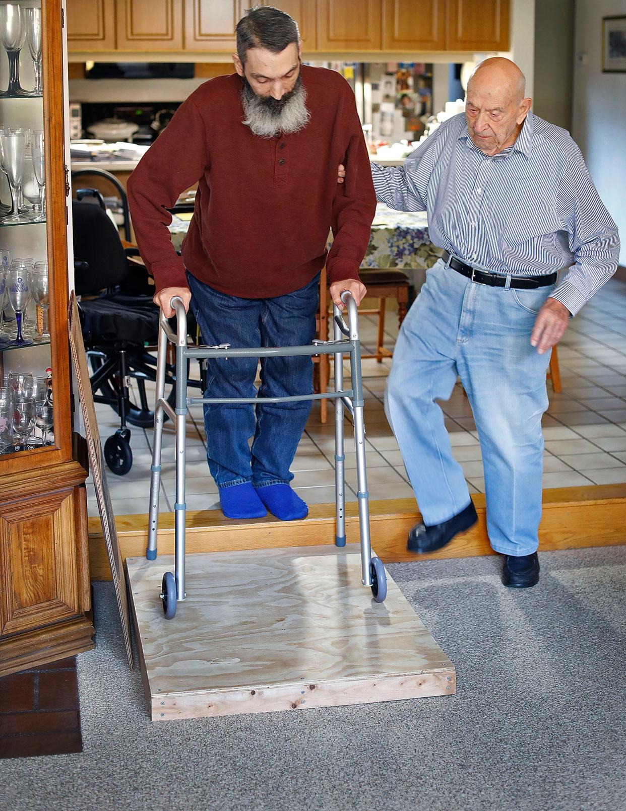 Carmine "Charlie" Mazzulli, 95, right, assists his son, Bob, 53, who suffered a spinal cord injury 10 years ago.