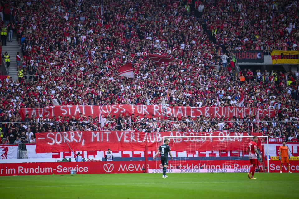 SC Freiburg fans hold up a poster reading "Fist instead of kiss for Rubiales and Rummenigge - sorry, absolutely okay if you'll pardon me" during the German Bundesliga soccer match between SC Freiburg and Werder Bremen at the Europa Park Stadium in Freiburg im Breisgau, Germany Saturday Aug. 26, 2023. (Tom Weller/dpa via AP)