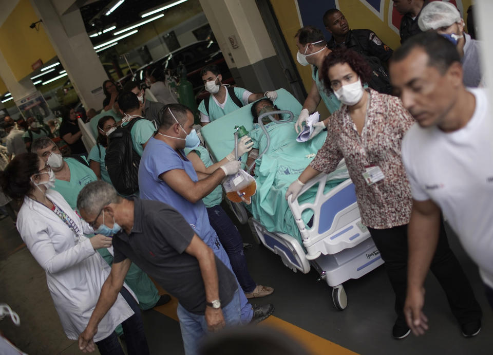 A patient is evacuated from the Bonsucesso Federal Hospital while firefighters douse a fire in Rio de Janeiro, Brazil, Tuesday, Oct. 27, 2020. According to the fire department, there were no casualties. (AP Photo/Silvia Izquierdo)