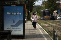 A woman wearing a face mask to protect against coronavirus waits to catch a tram during a gradual lifting of a lockdown to prevent the spread of the coronavirus, COVID-19, in Brussels, Monday, May 4, 2020. Belgium is relaxing some of its lockdown measures Monday. Business-to-business companies can open their offices to employees again and those taking public transport must wear a mask. (AP Photo/Francisco Seco)