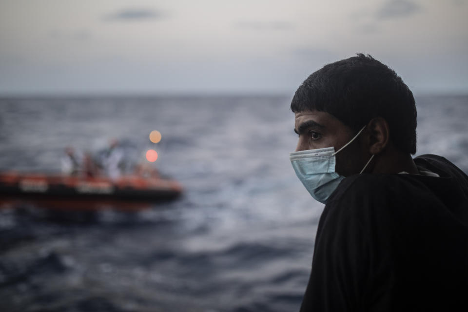 A migrant stands on on board the Spanish NGO Open Arms vessel with other people from different nationalities, including 14 minors and 4 women, on Wednesday Sept. 9, 2020, after being rescued last Tuesday night as they were trying to flee Libya on board a precarious wooden boat, in international waters, in the Central Mediterranean sea. (AP Photo/Santi Palacios)