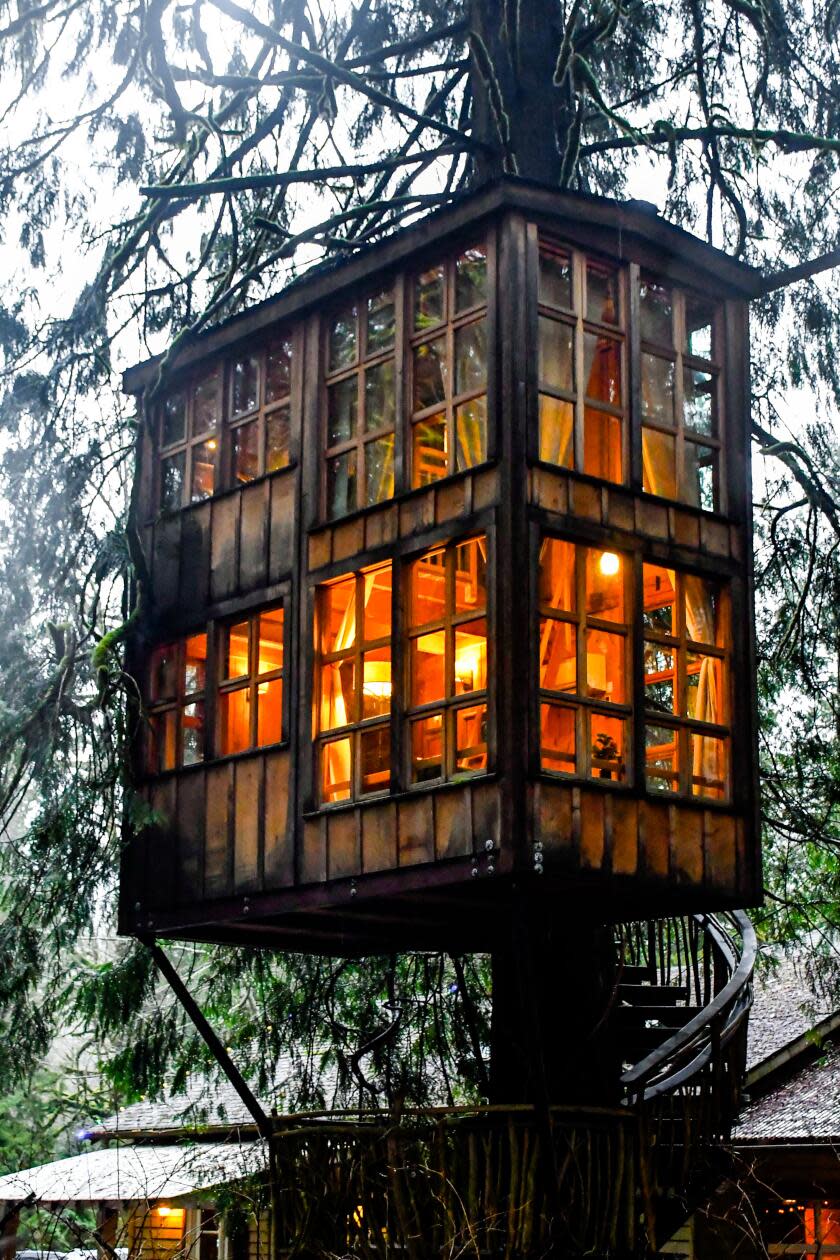 A two-story treehouse is all lighted up.